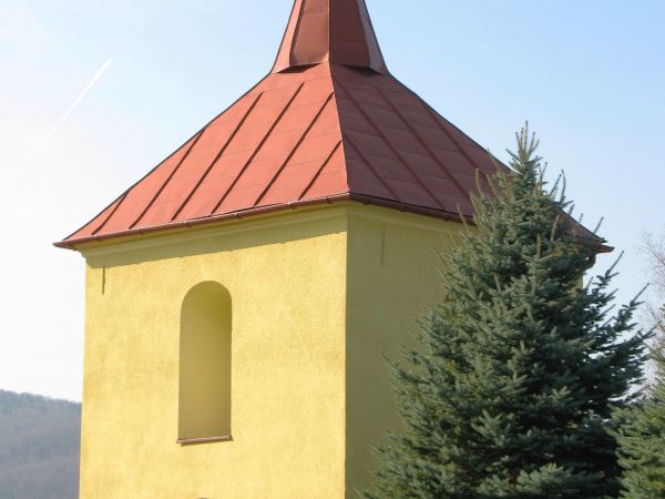 dzwonnica, na rzucie kwadratu, w przyziemiu bramka, górna kondygnacja przepruta z czterech stron półkolistymi arkadami.