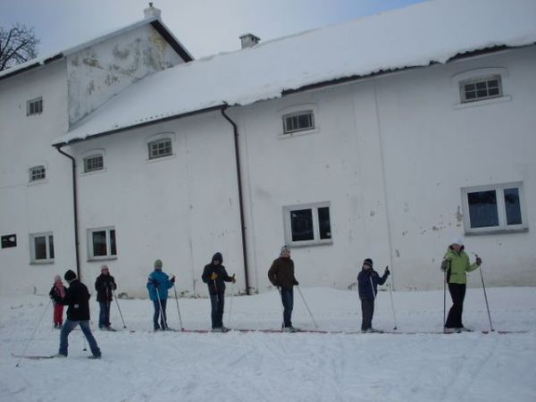 W tle gorzelnia, a na pierwszym planie młodzież na biegówkach