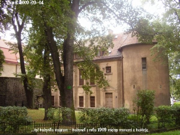Budynek Muzeum Ceramiki z basteją widziany od tyłu (skweru), w mur forteczny wstawione epitafia