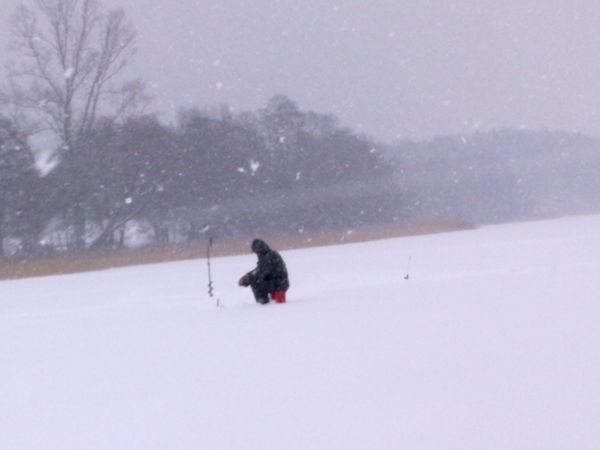 Zasypane śniegiem jezioro Łąke, a na nim wędkarze podlodowi.