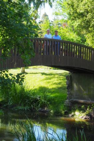 reprezentacyjny arkadowy mostek nad potokiem łączącym stawy w parku dworskim.