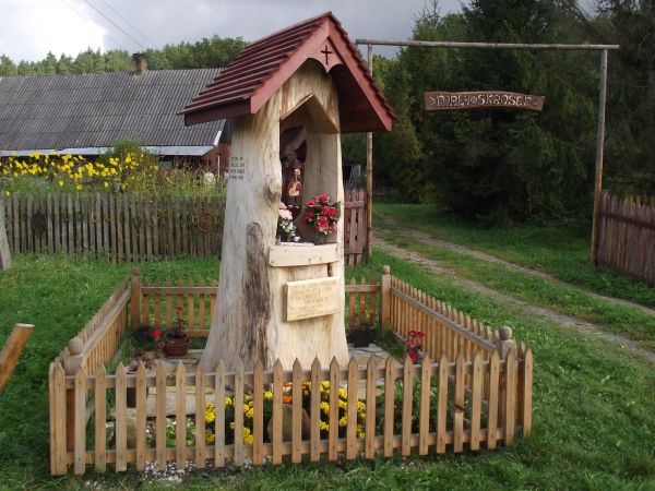 przed "bramą z powitaniem" otoczona płotkiem kapliczka z rzeźbą Chrystusa Frasobliwego.