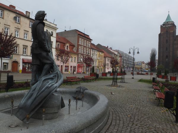 Chojnowski Rynek z kościołem p.w Piotra i Pawła widocznym na drugim planie a na pierwszym planie fontanna z figurą tkacza