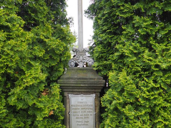 w otoczeniu cerkwi pomnik nagrobny - krzyż na postumencie z tablicą wotywną.