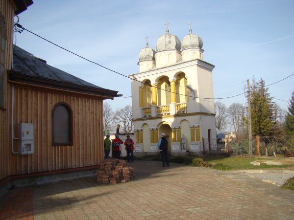 obok świątyni stoi dzwonnica murowana, trójkopułowa, z 1905 roku, z przejściem  w dolnej środkowej arkadzie, po prawej od tej arkady - figura św. Andrzeja, prze