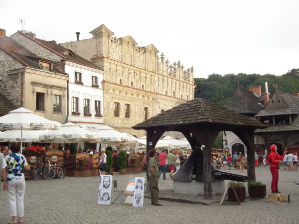 Urokliwy rynek ze studnią a w tle kamienica Przybyłów
