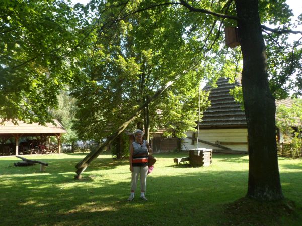 Zagroda - Muzeum, zrębowa studnia z żurawiem, dalej po lewej kierat - tu koło napędowe mechanizm uruchamiany ruchem okrężnym konia zaprzęgniętego do widocznego