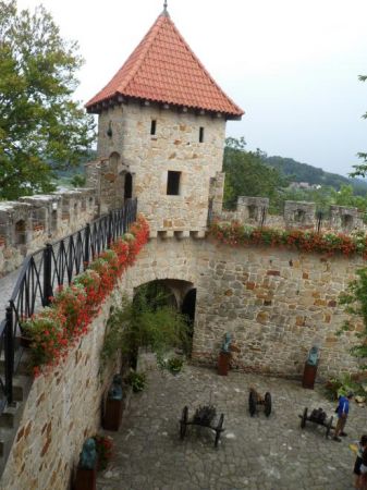 starannie i wiernie odrestaurowane mury forteczne z linią obronną - krenelażem, bajecznie prezentująca się baszta, w dole jeden z dziedzińców zamkowych z ekspoz