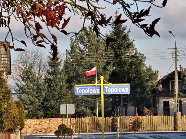 Znak ulicy Topolowej na tle zabudowań przy ulicy Polnej