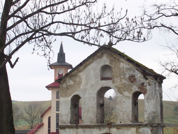 dzwonnica cerkiewna, dalej droga Lesko - Polańczyk - Wołkowyja, przy niej plansza z mapą i informacjami o okolicy, za drogą nowy kościół.