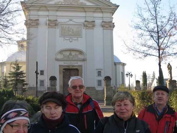 Przed kościołem pw. św. Wawrzyńca, późnobarokowym, kamiennym. Ufundowany w 1780r. przez Józefa Ossolińskiego z Tęczyna, wojewodę wołyńskiego, którego prochy spo