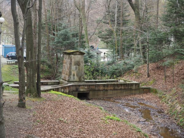 spływa potok Bełkotka i jest betonowy taras, pod nim śluza co pozwala na regulowanie wód potoku, na tarasie obelisk, na nim marmurowa tablica - to  tzw. "Pamiąt