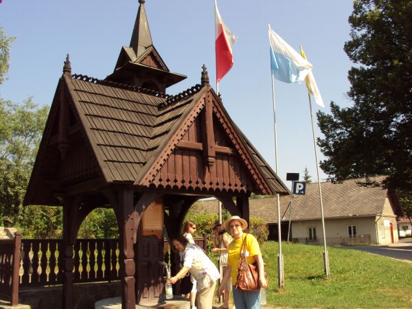 Stylistycznie "ze smakiem" zadaszone ujęcie wody z cudownego źródełka - przed i obok gł. wejścia murów przykościelnych. Dalej już : zabudowania gospodarskie. Je