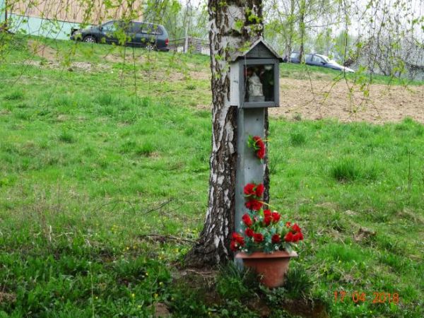 kapliczka przydrożna - tzw. skrzynkowa, pięknie ukwiecona, zawieszona na brzozie, we wnęce Pieta - Matka Boża Bolesna.