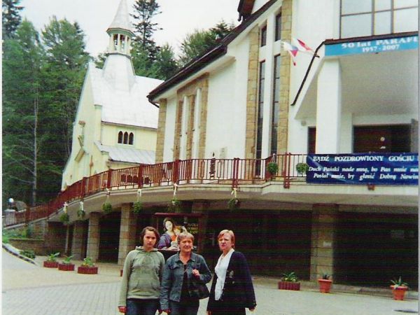 na zdjęciu: przed nowym kościołem parafialnym. W jego cieniu wznosi się stary drewniany kościół pw.  św. Iwona i Matki Bożej Uzdrowienia Chorych -  z 1838r. Do