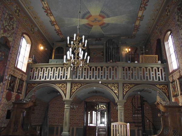 z nawy głównej widok na strop / sklepienie i polichromię sufitową oraz chór z organami, boazerią zdobiącą parapet i arkadowe wsporniki oraz spiralne schody, wid