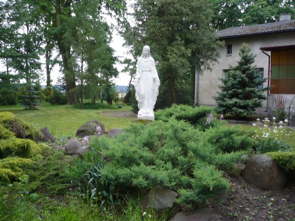 Zieleń przy parafii i figurka Matki Bożej.