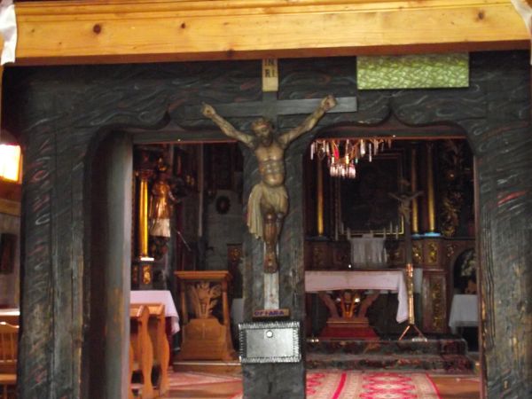 do kościoła wchodzimy przez bliźniacze odrzwia wycięte w "ośli grzbiet", wewnątrz centralnie na belce wspornikowej : krucyfiks - 1-sza poł. XIX wieku, a wcześni