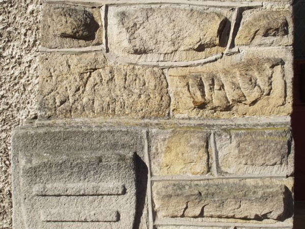 w portalu: herb Korczak - w oryginale byłoby: w polu czerwonym trzy wręby srebrne w pas, zwężające się w dół. Herb ma pochodzenie węgierskie, trzy wręby oznacza