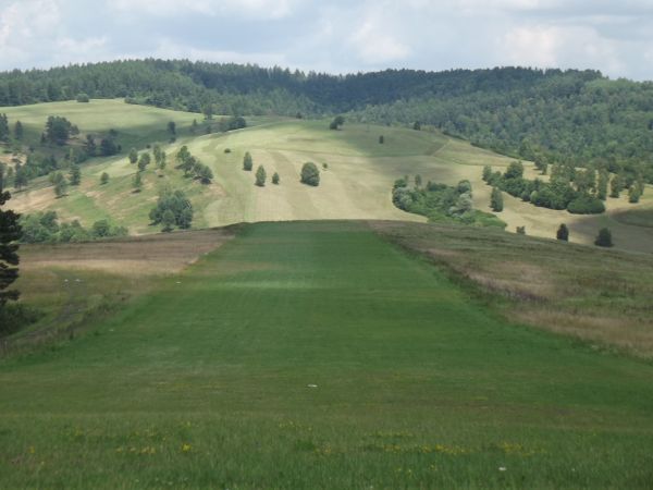 za zalesionym wzgórzem: Żerdenka a bliżej - po opuszczeniu zbocza pasma Markowskiej - w dolinie potoku Ruchlin - teren wsi Żernica Wyżna, z cerkwią a dalej na z