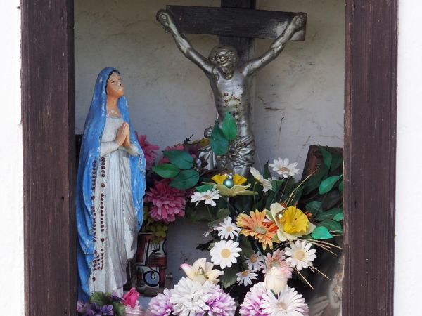 krzyż i figurka Matki Boskiej w głębokiej i otoczonej ramą niszy kapliczki po lewej drogi do m. Ulucz.