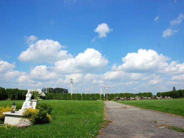 Cmentarz w Terliczce. Za ogrodzeniem widoczne szyby wiertnicze kopalni gazu ziemnego