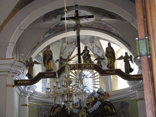 półkolumny, które w tle pseudopilastrów wspierają wydatny profilowany gzyms, który wygina się półkoliście nad kolumnami, na zdjęciu: częściowo widoczna polichro