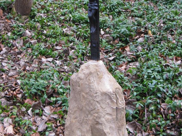 krzyż żeliwny - osadzony w kamiennym trzpieniu, który stanowi cokół nagrobka cmentarnego, łany barwinka ścielą się po cmentarzu cerkiewnym.