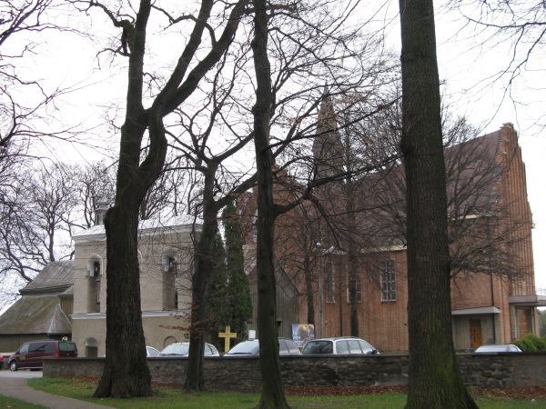 fragment parku podworskiego z murem a dalej dzwonnica, stary i nowy kościół.