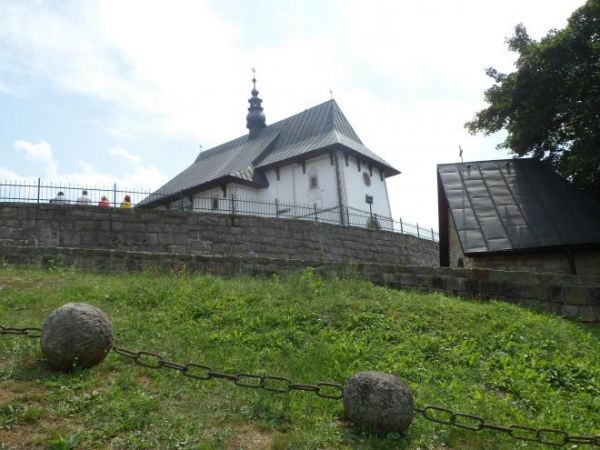 przed kościołem na obwarowanym kamieniami tarasie niżej - po prawej kaplica cmentarna z XVw.  a niżej splecione ogniwami łańcucha - kamienne paciorki Różańca Po