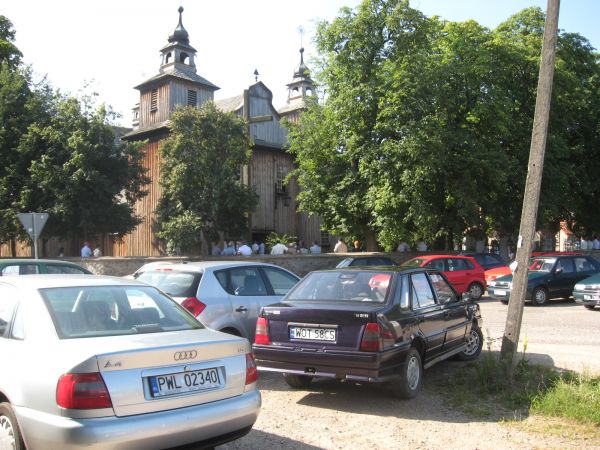 Kścół niedzielna msza na placu samochody parafian,bawniej to były furmanki