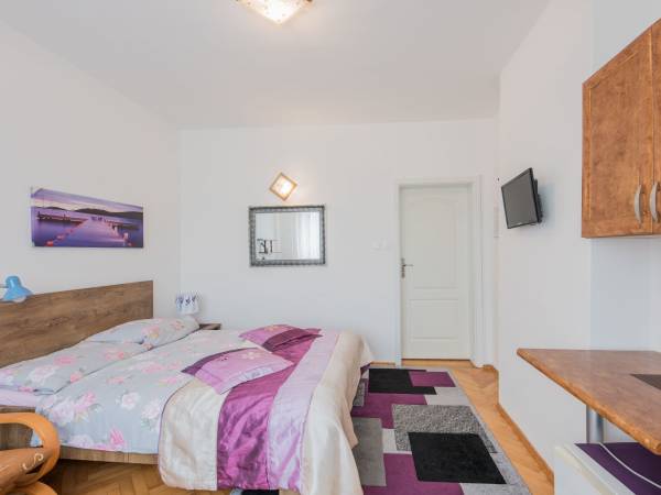 widok na pokój 3 osob. z małym aneksem kuchennym oraz TV.