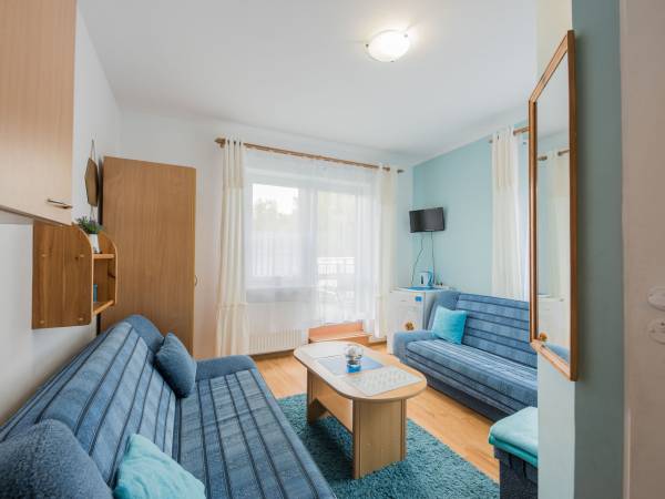 Widok na pokój 3 oso. z wyjściem na taras, gdzie można zjeść posiłek oraz wypić kawę lub się opalać.