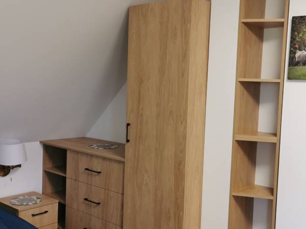 Pokój w nowym domku. Wyposażenie: szafa z półkami i komoda z szufladami. 