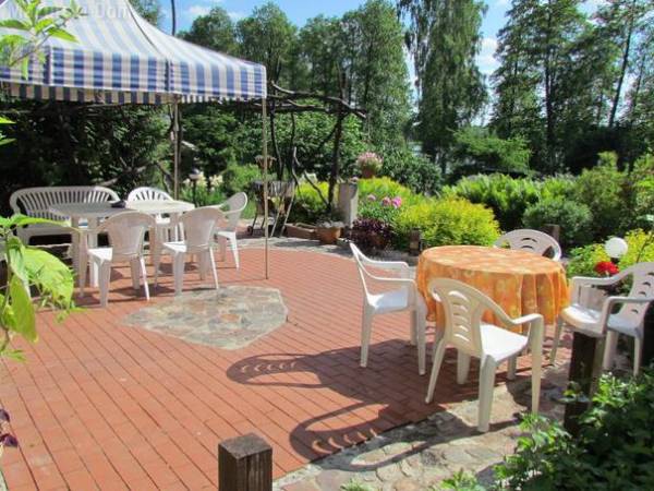 Taras z widokiem na jezioro otoczony jest w całości zielenią.