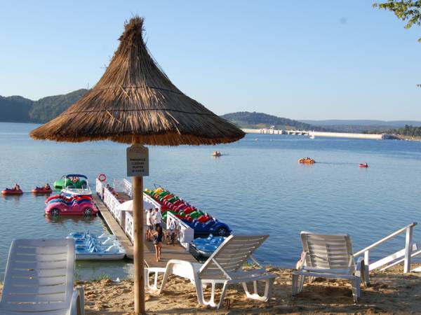 Plaża na cyplu, a w oddali zapora wodna w Solinie