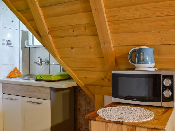 mini aneks z kuchenka mikrofalową, czjanikiem bezprzewowowym, zlewem i podstawowymi naczyniami