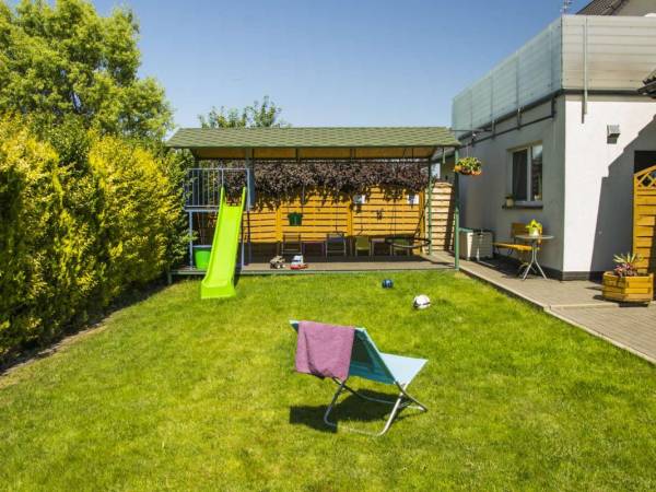 Ogród z placem zabaw, strona zachodnia. Pod tarasem część kuchenno-świetlicowa.